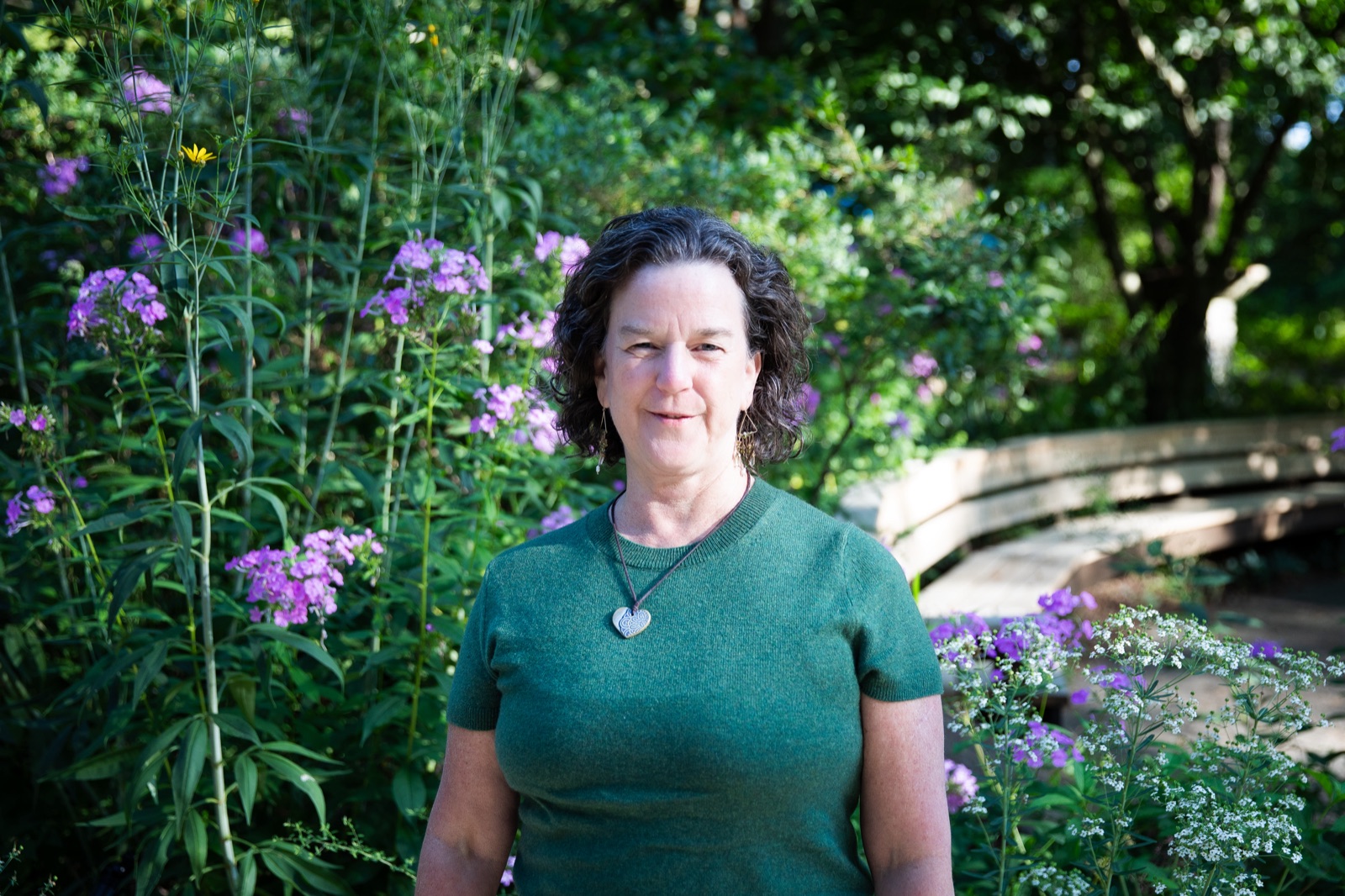Dr. Meg Moss smiling outdoors among flowers and greenery