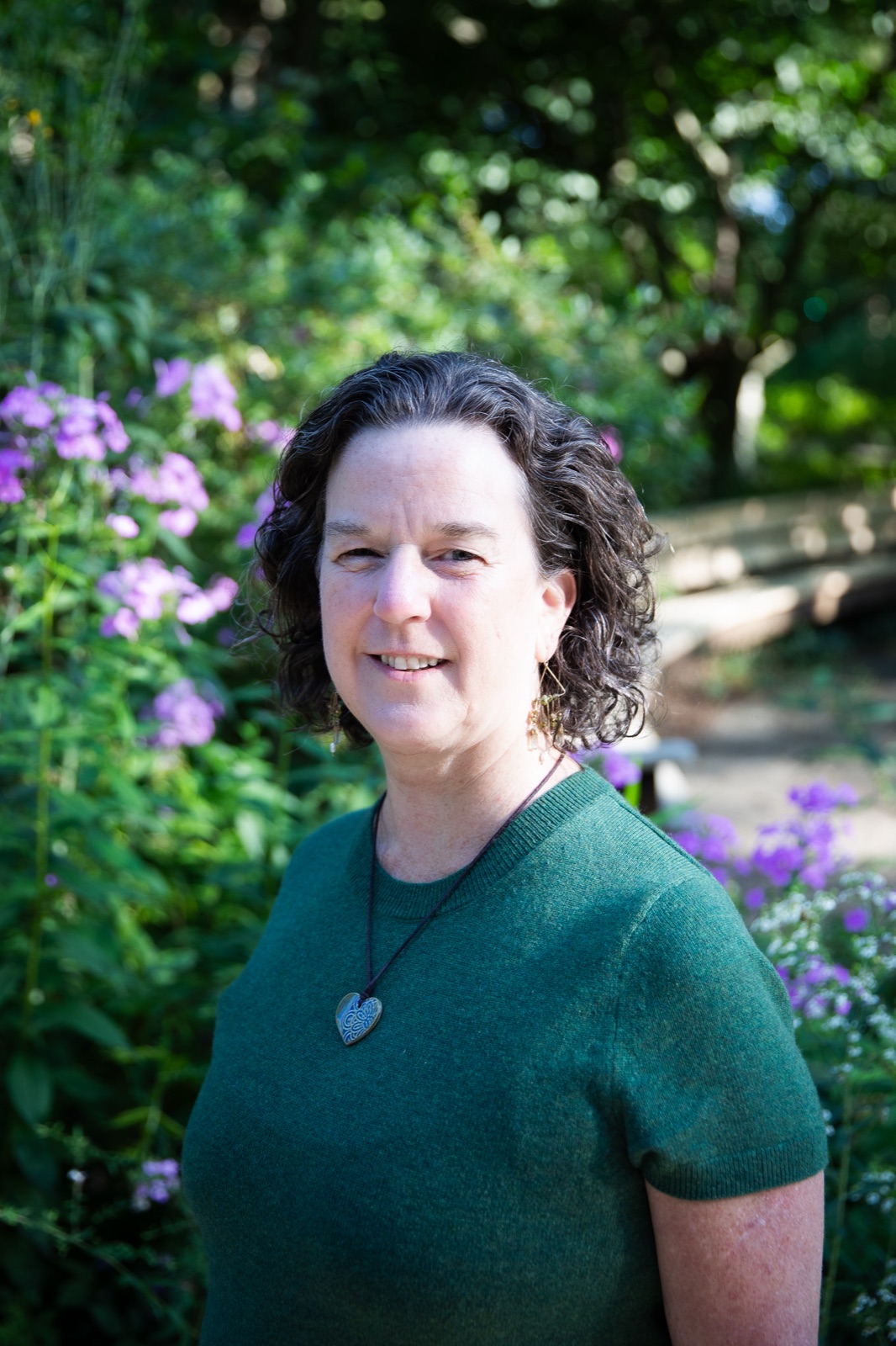 Dr. Meg Moss standing in a garden of purple flowers